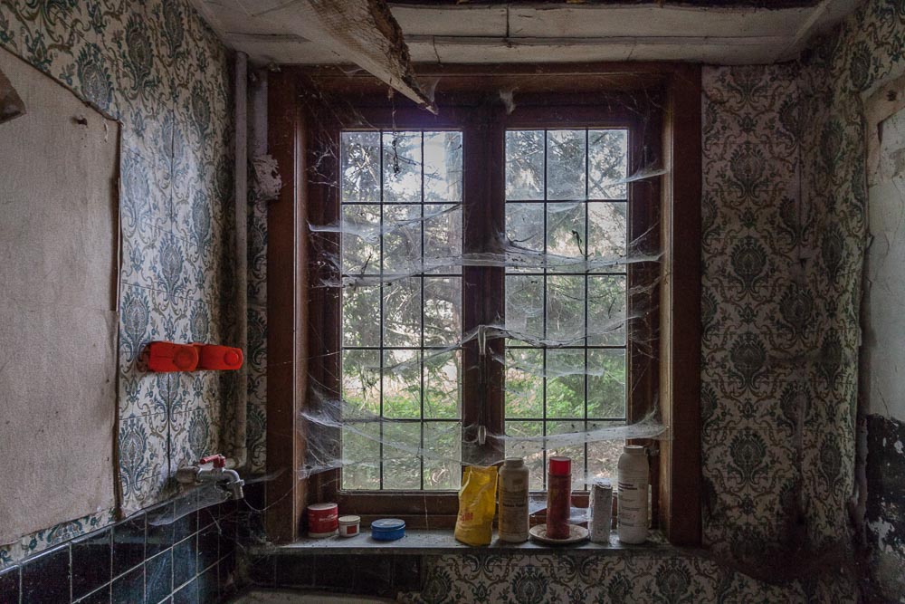 beeld van de keuken van de urbex locatie ferme tapioca,
            een verlaten boerderij waar spinnenwebben tot het decor behoren